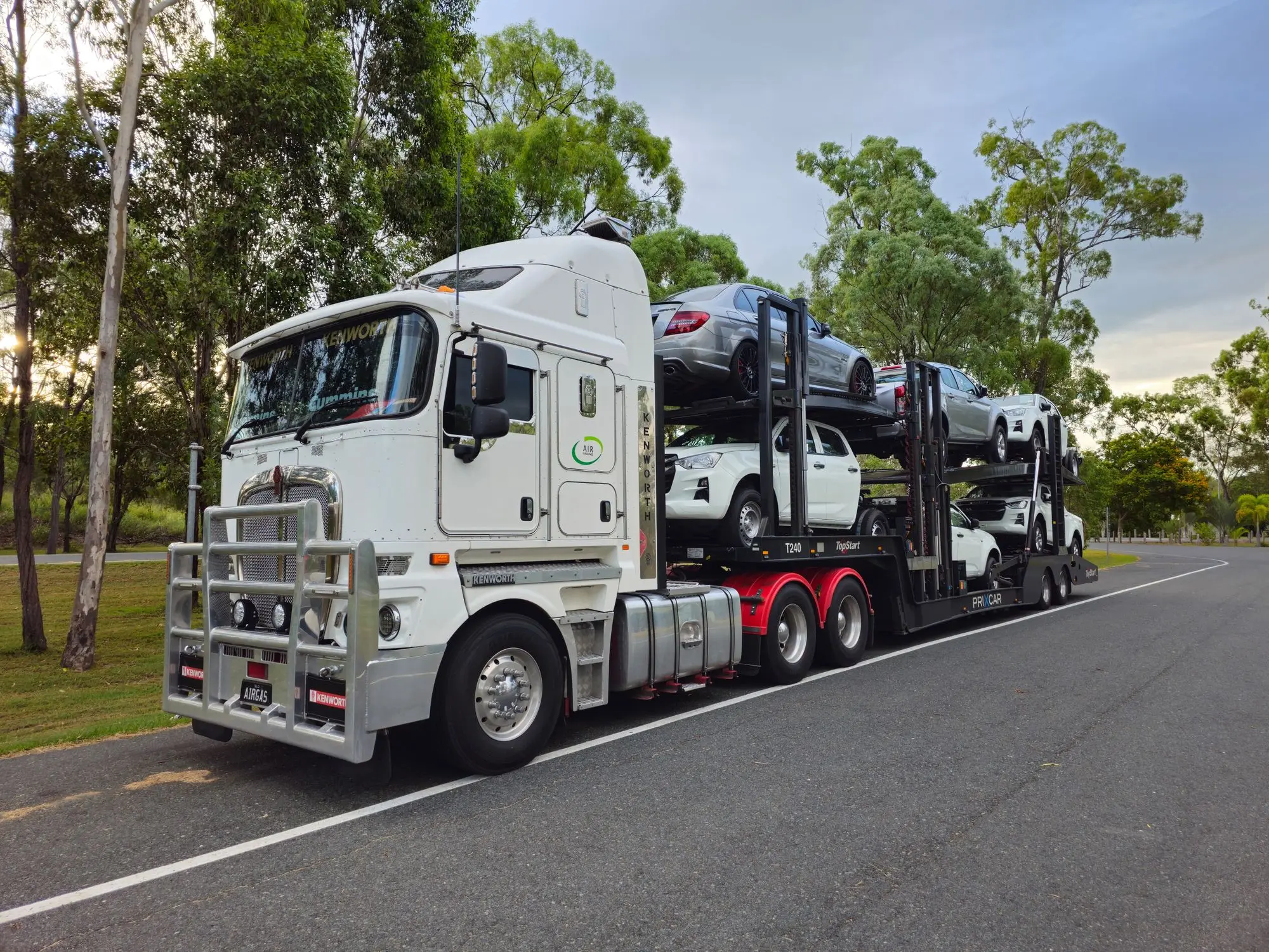 Kenworth prime mover hauling a loaded car-carrier trailer on a road in Heathwood, Queensland
